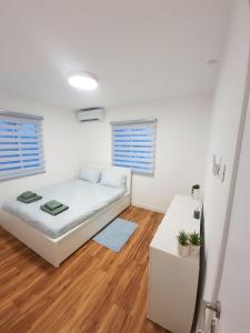 um quarto branco com uma cama e pisos em madeira em ביקתה בים em Tel Aviv