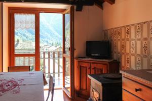 a kitchen with a television and a balcony with a view at Appartamento Gaby Gressoney CIR 006 in Gaby