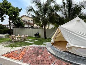 une tente dans une cour avec une table et des chaises dans l'établissement Lasam Heritage Villa + Glamping in the House 24pax with Karaoke & Snooker, à Ipoh