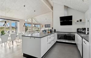 a kitchen with white cabinets and a black counter top at Amazing Home In Hvide Sande With House A Panoramic View in Havrvig