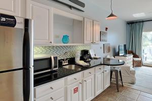 cocina con armarios blancos y encimera negra en Inn at Seacrest #206, en Rosemary Beach