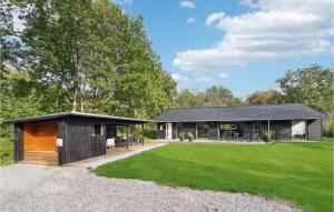 ein Haus mit einem schwarzen Dach und einem grünen Hof in der Unterkunft Gorgeous Home In Oksbl With Sauna in Oksbøl