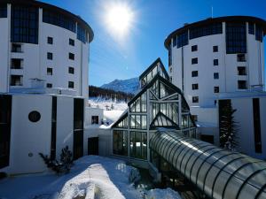 a building with a slide in the snow next to two buildings at Hotel Club Uappala Sestriere in Sestriere