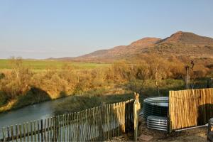 a fence next to a river with mountains in the background at Tugela River Lodge in Winterton