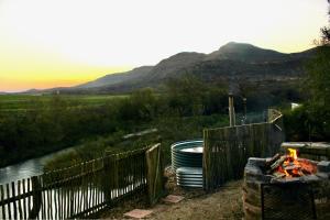 a fence next to a fire next to a river at Tugela River Lodge in Winterton