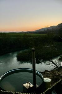 a hot tub next to a river at sunset at Tugela River Lodge in Winterton