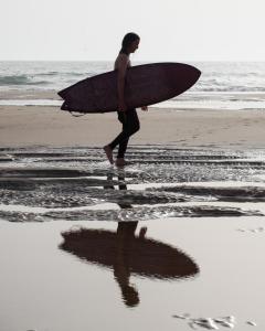 a man walking on the beach with a surfboard at Desart Hostel in Agadir