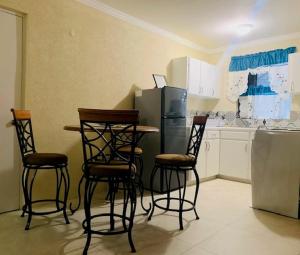 a kitchen with four chairs and a table and a refrigerator at Kenridge Residences in Saint James