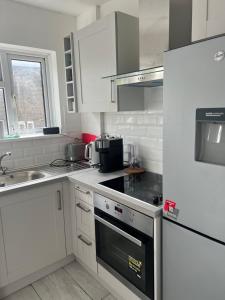 La cuisine est équipée de placards blancs et d'un four avec plaques de cuisson. dans l'établissement Just Plan B Homes, à Forest Hill