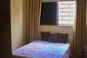 a small bed in a room with a window at Casa em condomínio, churrasqueira privativa e piscina social in Caldas Novas