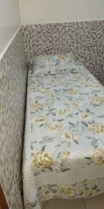 a bed with a blanket with flowers on it at Casa em condomínio, churrasqueira privativa e piscina social in Caldas Novas