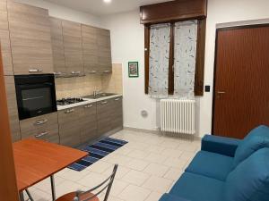 sala de estar con sofá azul y cocina en Casa Pompei, en Vigevano