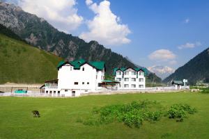 a large white building in a field with a cow at Lemon Tree Hotel, Sonamarg in Sonāmarg