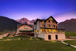 a large building on a hill with mountains in the background at Lemon Tree Hotel, Sonamarg in Sonāmarg