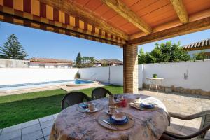 un patio con mesa, sillas y piscina en Las Golondrinas, en Chiclana de la Frontera