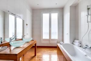 a bathroom with three sinks and a bath tub at Sweet Inn - Rue de Ponthieu in Paris