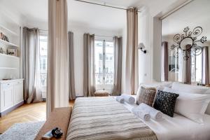 a white bedroom with a large bed with a large mirror at Sweet Inn - Rue de Ponthieu in Paris