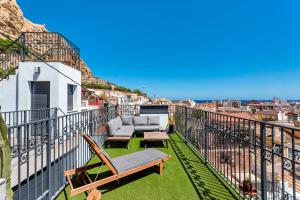 einen Balkon mit einem Sofa und Stühlen auf einem Gebäude in der Unterkunft LUXURY EVOLUTION ROOMS in Alicante