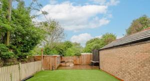 um quintal com uma parede de tijolos e um relvado em Extensive 4 bed close to Peterborough em Ramsey