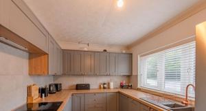 cocina con armarios de madera, fregadero y ventana en Extensive 4 bed close to Peterborough, en Ramsey