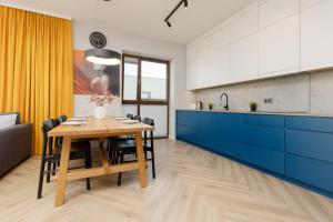 a kitchen with a wooden table and blue cabinets at Cozy & Spacious Family Apartment by Renters in Warsaw