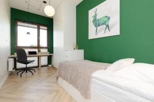a bedroom with green walls and a bed and a desk at Cozy & Spacious Family Apartment by Renters in Warsaw