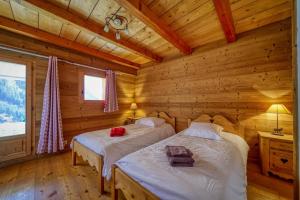 1 dormitorio con 2 camas en una cabaña de madera en Chalet Beaufortain La Pachna, en Hauteluce