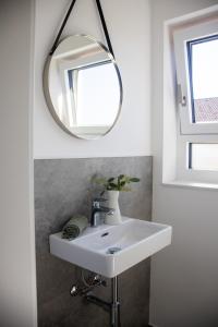 een badkamer met een witte wastafel en een spiegel bij Elmi 33 in Wals