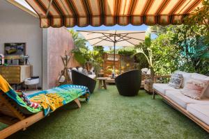 eine Terrasse mit einem Sofa, Stühlen und einem Sonnenschirm in der Unterkunft Domaine de la Corniche in Saint-Raphaël