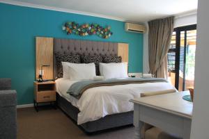 1 dormitorio con 1 cama grande y pared azul en Pelican Lodge Guesthouse, en Sedgefield