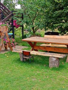 a wooden picnic table and a bench in the grass at DOMEK LETNISKOWY PRZY GÓRACH MAJOWYCH in Goniadz