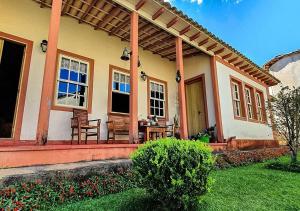 a house with a porch with chairs and a table at Pousada Quinta Do Conde in Tiradentes
