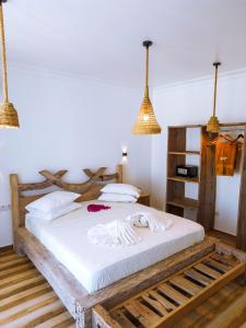 a bedroom with a bed with white sheets and pendant lights at Limiria Villa Zanzibar in Nungwi