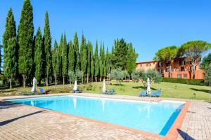 a swimming pool with chairs and trees and a building at Pian Dei Mucini Resort in Massa Marittima