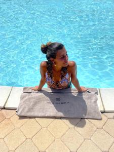 una mujer sentada en una toalla junto a una piscina en Pian Dei Mucini Resort, en Massa Marittima
