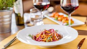 un plato blanco de comida en una mesa con copas de vino en Pian Dei Mucini Resort, en Massa Marittima