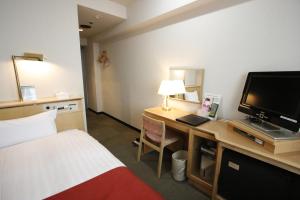 a hotel room with a bed and a desk with a television at Hotel Abest Meguro in Tokyo