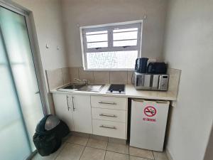 a small kitchen with a sink and a microwave at Sea Breeze Manor - Aqua Unit in East London
