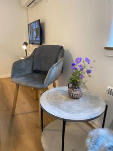 una silla y una mesa con un jarrón de flores. en Ferielejlighed til 2 personer en Ebeltoft