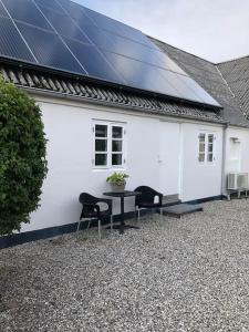 une maison blanche avec une table, des chaises et des panneaux solaires dans l'établissement Ferielejlighed til 2 personer, à Ebeltoft