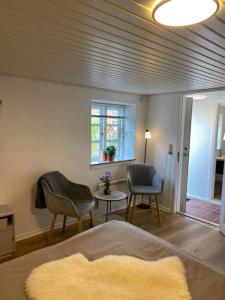 a bedroom with a bed and chairs and a window at Ferielejlighed til 2 personer in Ebeltoft