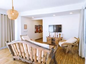 a living room with a couch and chairs and a tv at Limiria Villa Zanzibar in Nungwi