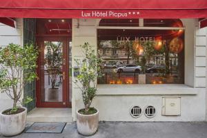 a store front with two potted trees in front of it at Hôtel LUX PICPUS in Paris