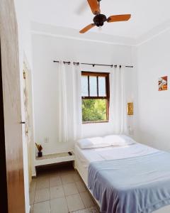 um quarto branco com uma cama e uma janela em Recanto da Floresta Suites em Ubatuba