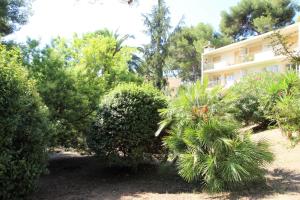 un edificio rodeado de árboles y arbustos en La Cigale Sanaryenne classé 4 étoiles face à un jardin méditerraneen, en Sanary-sur-Mer