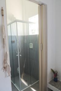 uma porta de chuveiro de vidro com um cão de pé nela em Recanto da Floresta Suites em Ubatuba