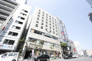 a tall white building with cars parked in front of it at Hotel Abest Meguro in Tokyo