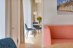 Blick auf ein Zimmer mit einem Tisch und Stühlen in der Unterkunft Elisapart - Apartments am Sommerschloss in Potsdam