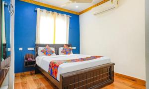 a bedroom with a bed with blue walls and a window at FabExpress Lloyds Inn in Chennai