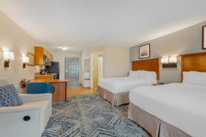 a hotel room with two beds and a couch at Candlewood Suites Indianapolis East by IHG in Indianapolis